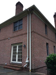 Gutter downspout on townhouse with deck